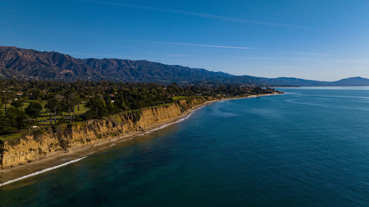 Stunning aerial view of Montecito coastline with pristine beaches, dramatic cliffs, and luxury homes nestled between mountains and ocean - Two Trees Cleaning service area